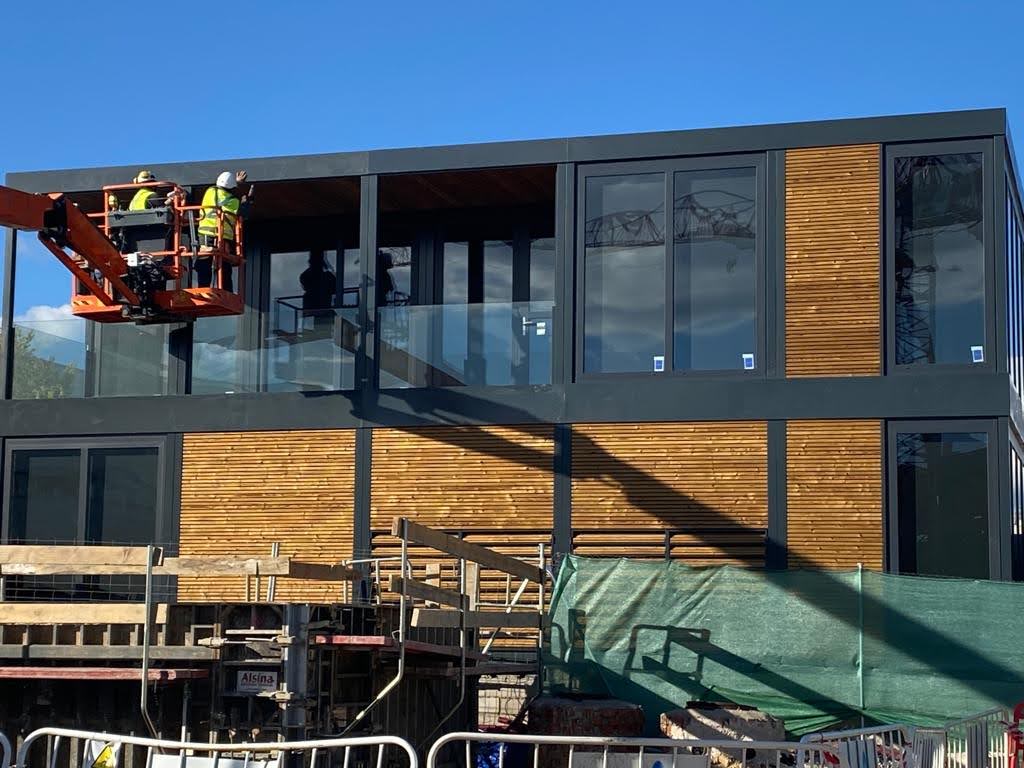 Oficina prefabricada exterior de doble altura con terraza y barandilla de vidrio estructural